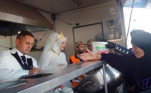 Fethullah Uzumcuoglu and Esra Polat dressed in traditional wedding clothes feeding the hungry on their wedding day.