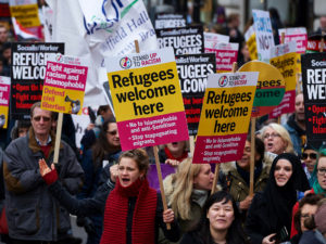 Demonstrators hold banners in support of refugees as they march through central London on March 19, 2016. (Photo credit NIKLAS HALLE'N - Getty Images)